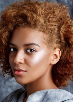 Young beautiful african girl looking at camera, posing, wrapping up  in grey cloth. Copy space.